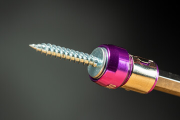 magnetic nozzle for a screwdriver, holds a self-tapping screw, black background