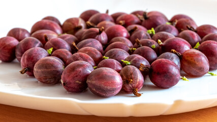 Ripe gooseberries on a white plate, gooseberry harvest