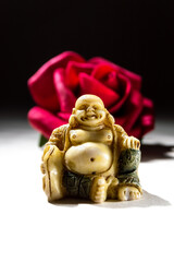 Fat Buddha with red rose and dark background