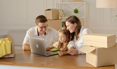 A Happy Family Uses a Laptop for Online Shopping, Sitting at Home.