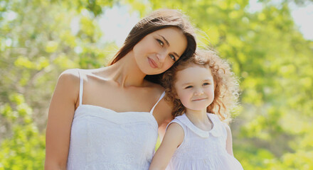 Fototapeta premium Portrait of happy mother and daughter child together in a sunny summer park