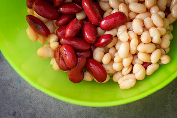 rote und weiße Bohnen einer grünen Kunststoff Schale mit grauem Hintergrund