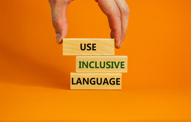 Use inclusive language symbol. Wooden blocks with words 'Use inclusive language'. Beautiful orange background, businessman hand. Business and use inclusive language concept. Copy space.