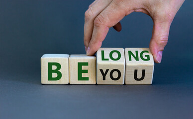 Be you, belong symbol. Businessman hand turns cubes and changes words 'be you' to 'belong'....