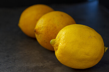 Drei Zitronen hintereinander aufgelegt versetzt auf dunklem Hintergrund