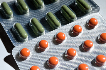 orange and green pills in a foil blister lie on a light background. large iplan. view from above