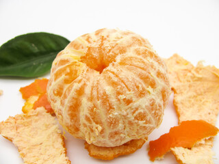 One orange peeled fresh tangerine on a white background among its peel.