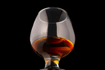Glass of cognac close up isolated on black background.