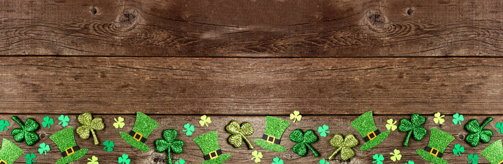St Patricks Day shamrock and leprechaun hat bottom border. Top down view over a rustic wood banner...
