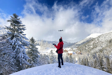 young men launching a drone for filming snowy mountains and winter landscape