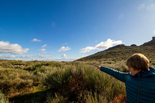Ni&ntilde;o con barrita m&aacute;gica en paisaje de oto&ntilde;o con cielo de nubes azul en el norte de Extremadura