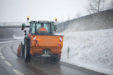 snow plow, winter service on a wet road, winter service truck driving on asphalt road at day while salting the asphalt to protect for freezing