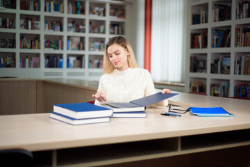 Portrait of clever student with open book reading it in college library.