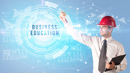 Handsome businessman with helmet drawing BUSINESS EDUCATION inscription, contruction business concept