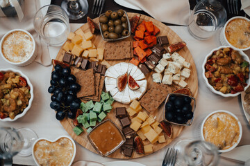 Cheese plate with chocolate, olives and grapes