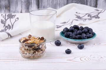 Healthy breakfast with muesli, milk and fresh blueberries on a white wooden table in a rustic style, close-up, horizontal