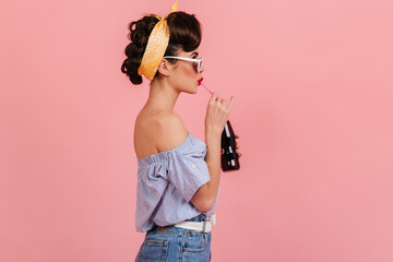 Side view of pinup brunette girl drinking soda. Studio shot of stylish young woman in vintage...