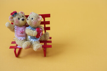 Figure of two funny bear cubs with a heart on a yellow background, side view, place for text-the concept of pleasant holidays © MARYIA