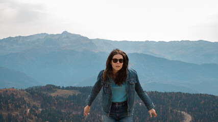 Naklejka premium Trekking in the mountains, a young woman jumps and has fun