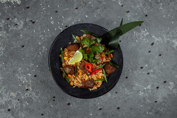 Fried rice with beef and vegetables on a gray textured background