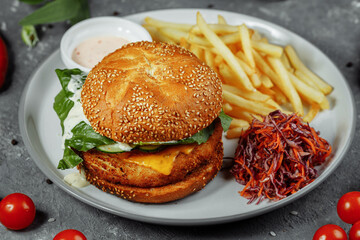 chicken burger with french fries and salad on an old concrete background