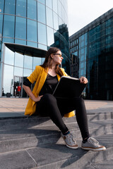 freelancer with a laptop sat on the steps near the business center,