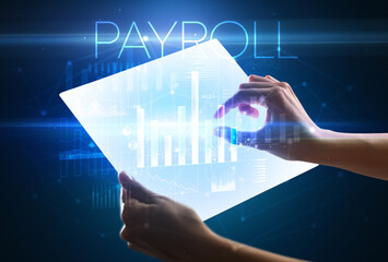 Hand holding futuristic tablet with PAYROLL inscription above, modern business concept