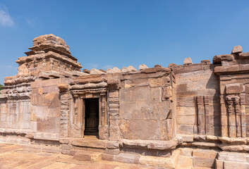 Fototapeta premium Aihole, Karnataka, India - November 7, 2013: Suryanarayana Temple under blue cloudscape. Heavily damaged brown stone building.