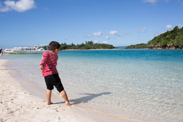 Little boy playing at Kabira Bay on Ishigaki Island, Okinawa, Japan with emerald blue and clear water on a sunny summer day.