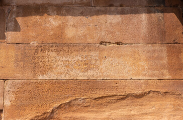 Aihole, Karnataka, India - November 7, 2013: Lad Khan Temple. Closeup of ancient script chiseled into brown stone wall.