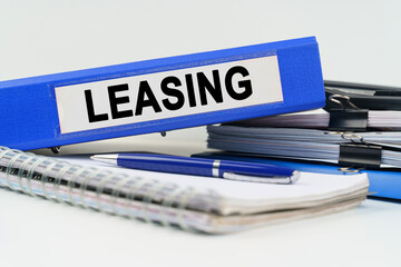 On the table are a notebook, a pen, documents and a folder with the inscription - LEASING