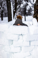 Portrait image of a young woman with blue eyes playing in a fort igloo in an enchanted snow-covered...