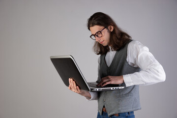 Training and new technologies, online courses, e-learning. A young man with long hair and glasses.
