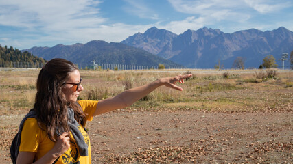 young female tourist with a backpack is walking in the mountains, traveling in national parks.
