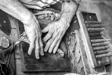 black and white with hands of a old man making cigars in cuba