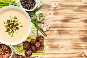 Delicious chestnut soup with croutons and herbs on a wooden table. Top view. Copy space.
