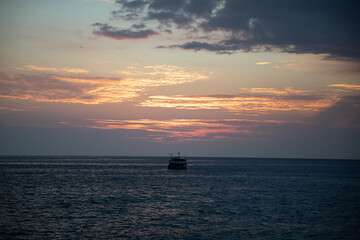Naklejka na ściany i meble sunset over the sea with a yacht centering the image