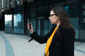 young woman wearing a coat and glasses uses a smartphone,