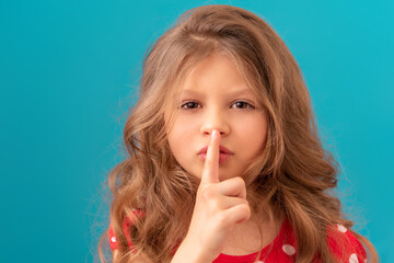 Fototapeta premium Little beautiful girl points her finger be quiet.