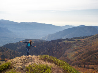 Fototapeta premium tourist stands on top of a mountain with her arms outstretched, Hiking in the mountains.