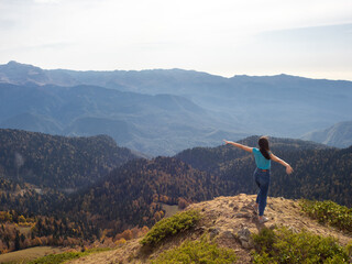 tourist stands on top of a mountain with her arms outstretched, Hiking in the mountains.