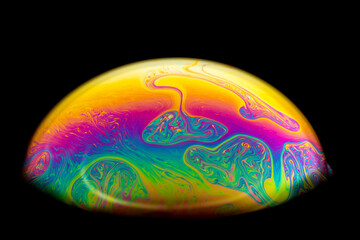Macro picture of half soap bubble on black background. psychedelic color for a wallpaper or...
