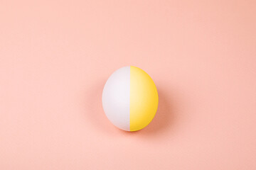 One Easter egg of different colors on a pink background.