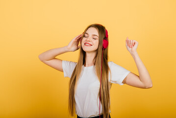 Portrait of beautiful cheerful female with long hair smiling looking at camera over yellow back.