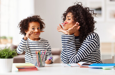 Ethnic mother and son grimacing and doing homework