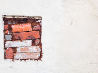 Red bricks stack in a old square shape window. White background at the right side. 