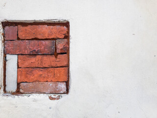 A hole filled with bricks. White wall background 