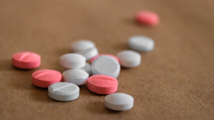 Close up of pink and white tablets on light bown background