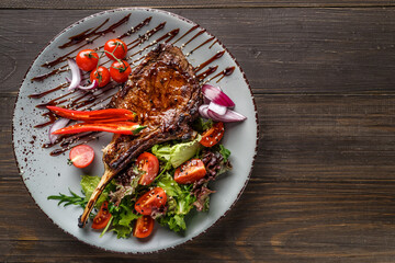 Grilled beef steak, herbs and spices on a dark table. Top view. Free space for your text.