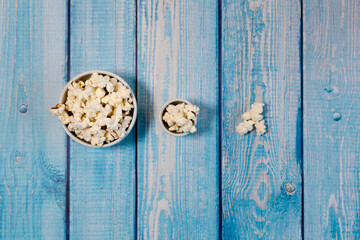 Popcorn bowls on blue wooden table.